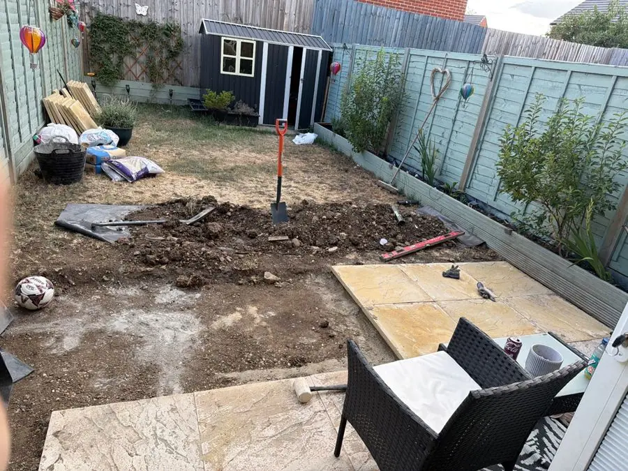 A dug up yard with soil, new slabs and rattan chairs, before the redesign