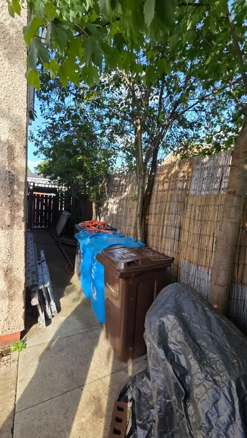 A narrow side passage cluttered with bins and tarpaulins, before the redesign