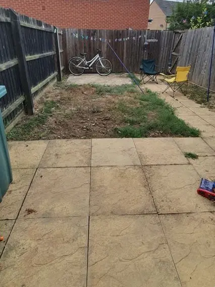 Plain patio slabs, a bare patch of lawn and a parked bike, before the redesign