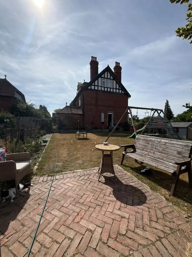 A herringbone brick patio, a bench, a lawn and a swing frame, before the redesign