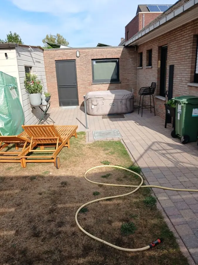A dry lawn with a hose, sun loungers and a hot tub, before the redesign