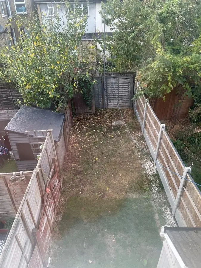 A narrow bare garden between fences with a shed, from above, before the redesign
