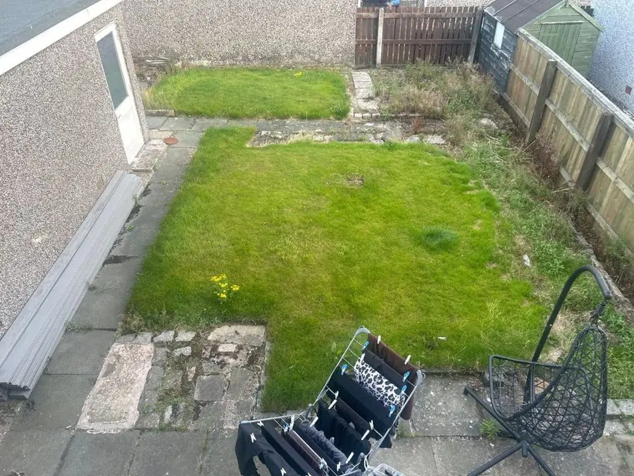 Neat lawn framed by grey paving: the garden before