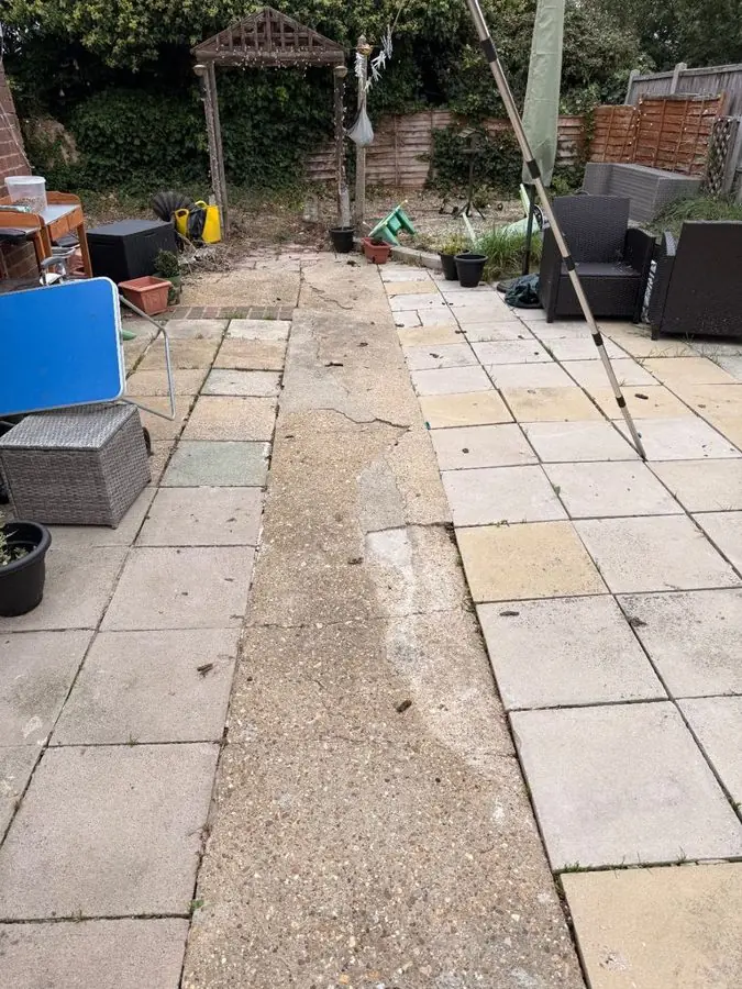 A cluttered paved patio with a wooden gazebo at the back, before the redesign