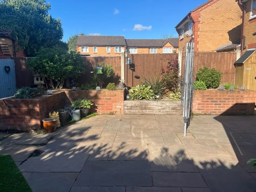 A paved patio with raised brick beds and a rotary washing line, before the redesign