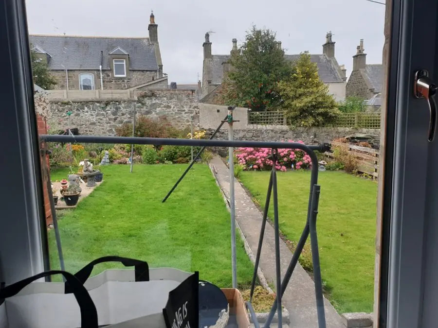 A lawn with a path down the side and a swing frame, before the redesign