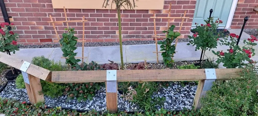 A front bed of grey chippings with a few roses behind a timber rail, before the redesign
