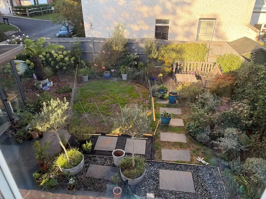 A small garden with slabs in gravel, a lawn patch and pots, before the redesign