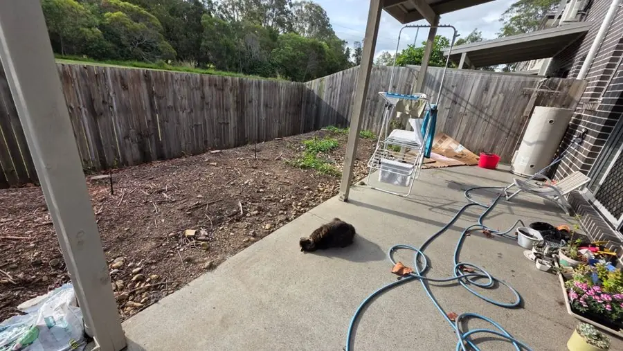 Bare earth beside a concrete patio under a canopy, before the redesign