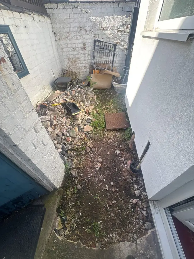 A narrow side passage full of rubble between white walls, before the redesign