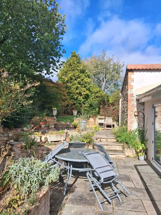 A patio with folding chairs and steps up to a raised garden, before the redesign