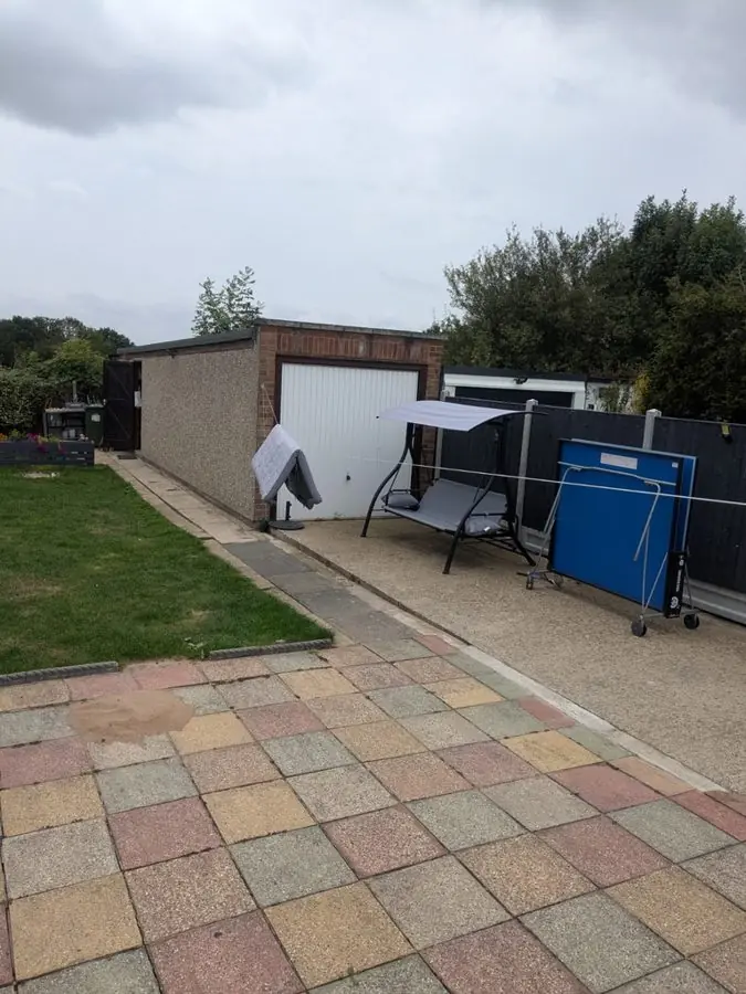 A coloured block patio beside a lawn, driveway and garage, before the redesign