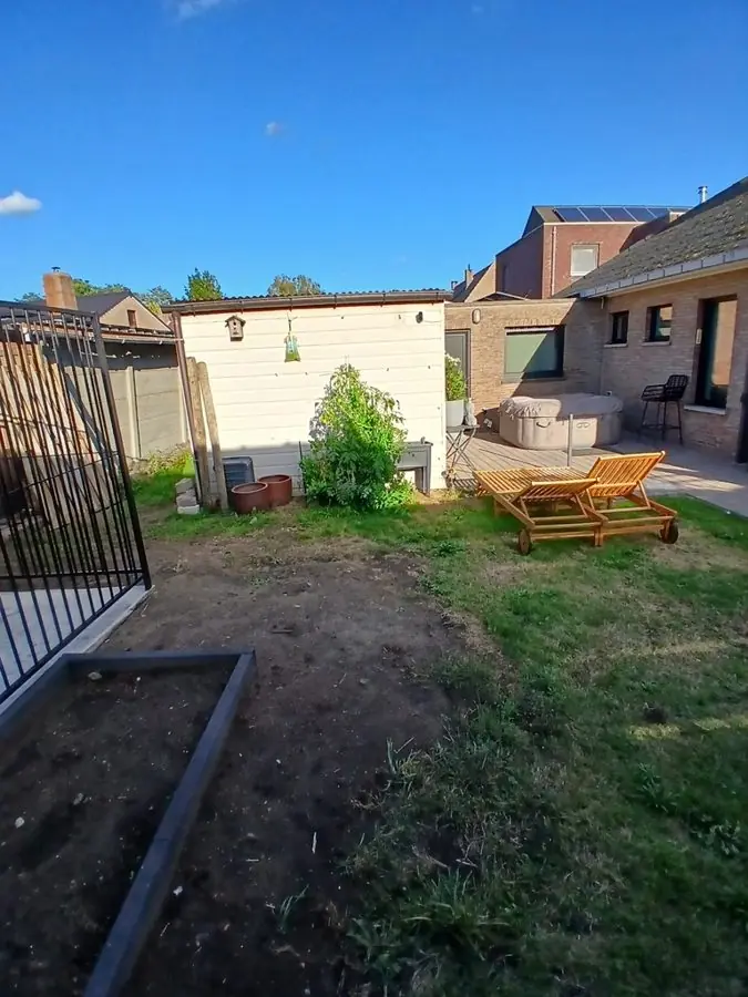 A patchy lawn and bare soil with loungers by a white shed, before the redesign