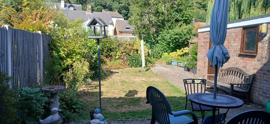 A lawn with a patio table, parasol and bird bath, before the redesign