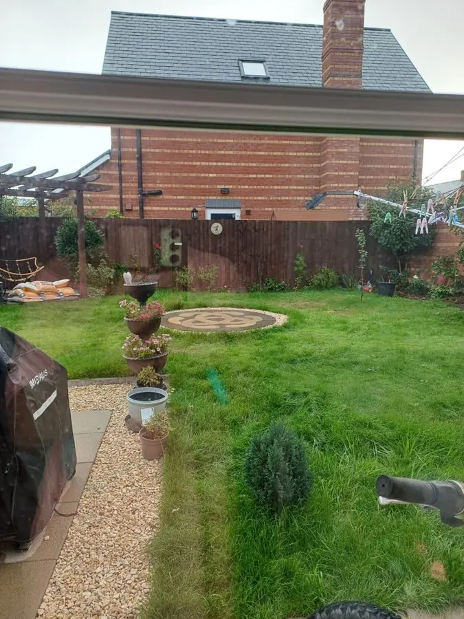 A lawn and gravel path, with a paved circle, seen through a window, before the redesign