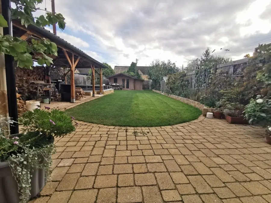 Block paving round an oval lawn with a timber shelter and shed, before the redesign