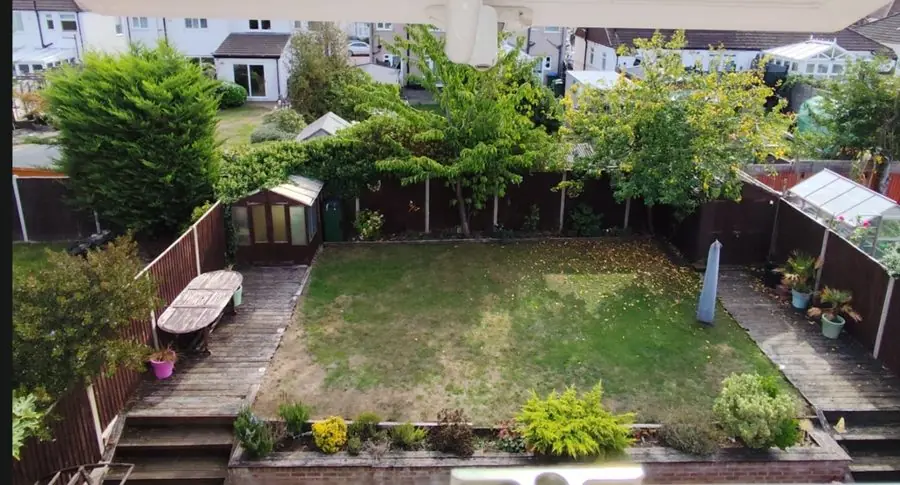 A square lawn with fences, a shed and greenhouse, seen from upstairs, before the redesign