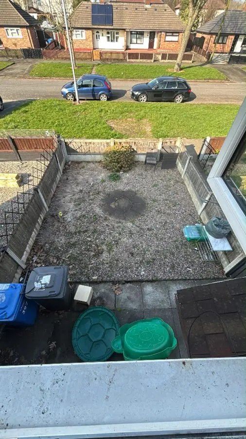 A bare gravel front yard with bins, seen from upstairs, before the redesign