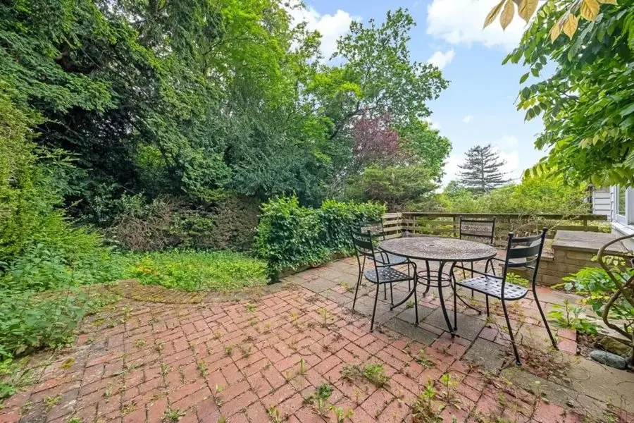 A weedy brick patio with a round table and chairs, before the redesign