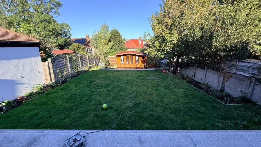 A plain lawn between fences with a summer house at the end, before the redesign