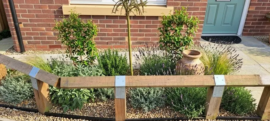 A bed by the front door of lavender, rosemary and an olive jar behind a sleeper rail, designed with the app