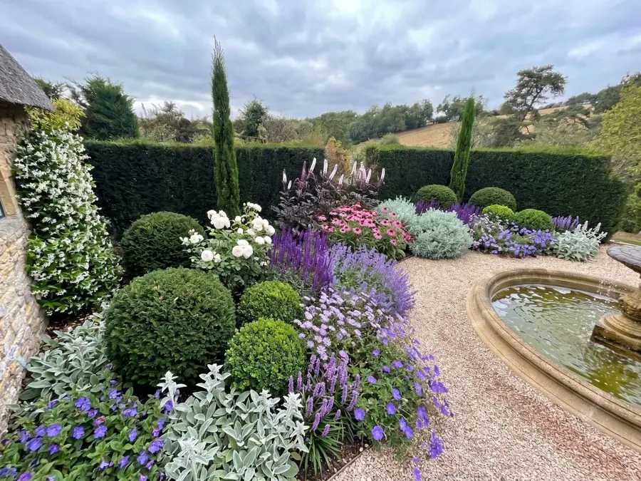 Clipped balls and cypresses beside a stone fountain, designed with the garden design tool