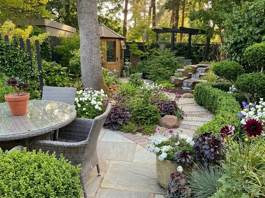 Clipped box and a stone path up to a small water cascade under a pine, designed with the app