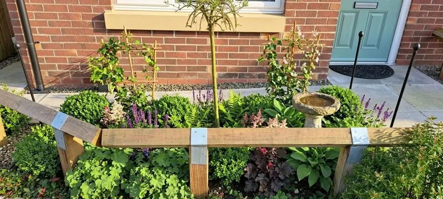 A new build's front bed of grey chippings, filled with hostas, ferns, salvias and a bird bath, an evergreen garden idea