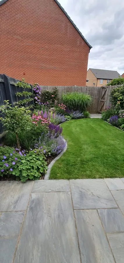 A new patio by a gable end, with a curving lawn and borders of salvias, redesigned with the app