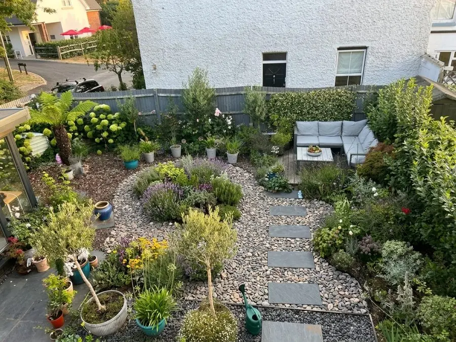 Seen from upstairs: a gravel circle and stepping stones among pots, an olive and grasses, designed with the app