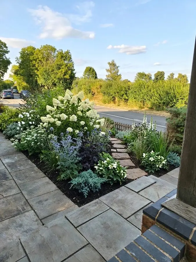 A sloping corner by the road planted with white hydrangeas and lavender beside the steps, a flower bed designed with the app